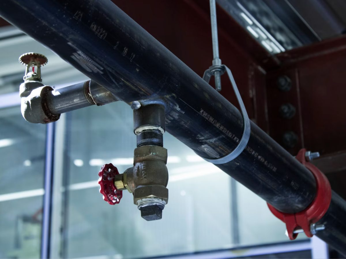 A brass shut-off valve on an overhead pipe assembly